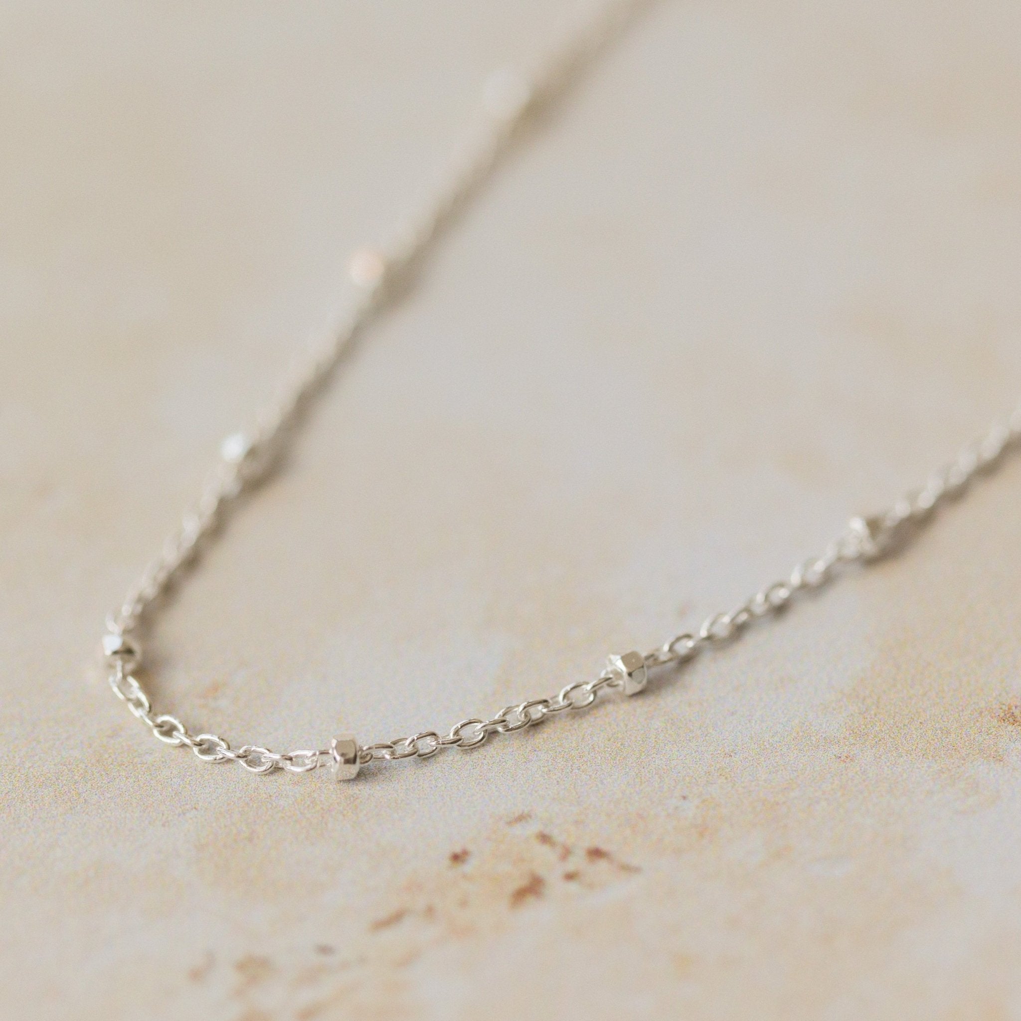 close-up of recycled silver satellite chain bracelet with delicate bead details on neutral background by Iris & Lolli