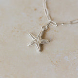 recycled silver starfish charm bracelet with paperclip chain photographed close-up on stone surface, handcrafted coastal jewellery by Iris & Lolli