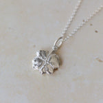 Handcrafted silver clover leaf necklace made from recycled silver. Organic textured pendant with botanical detail, a meaningful lucky clover jewellery gift.