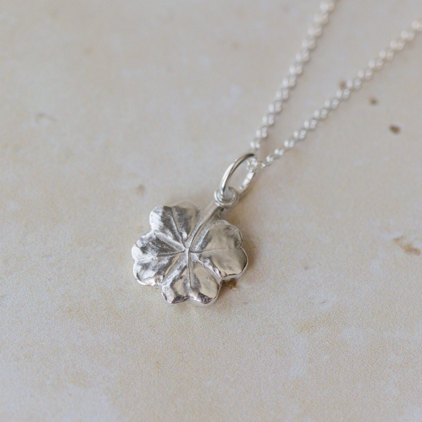 Handcrafted silver clover leaf necklace made from recycled silver. Organic textured pendant with botanical detail, a meaningful lucky clover jewellery gift.
