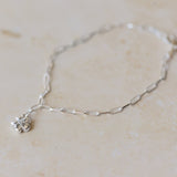 silver forget me not charm bracelet with paperclip chain styled flat on neutral background, delicate floral jewellery by Iris & Lolli