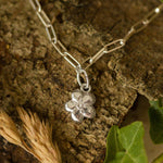 silver forget me not flower charm bracelet photographed on natural bark and foliage, handcrafted floral jewellery by Iris & Lolli