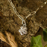 silver forget me not flower charm bracelet photographed on natural bark and foliage, handcrafted floral jewellery by Iris & Lolli