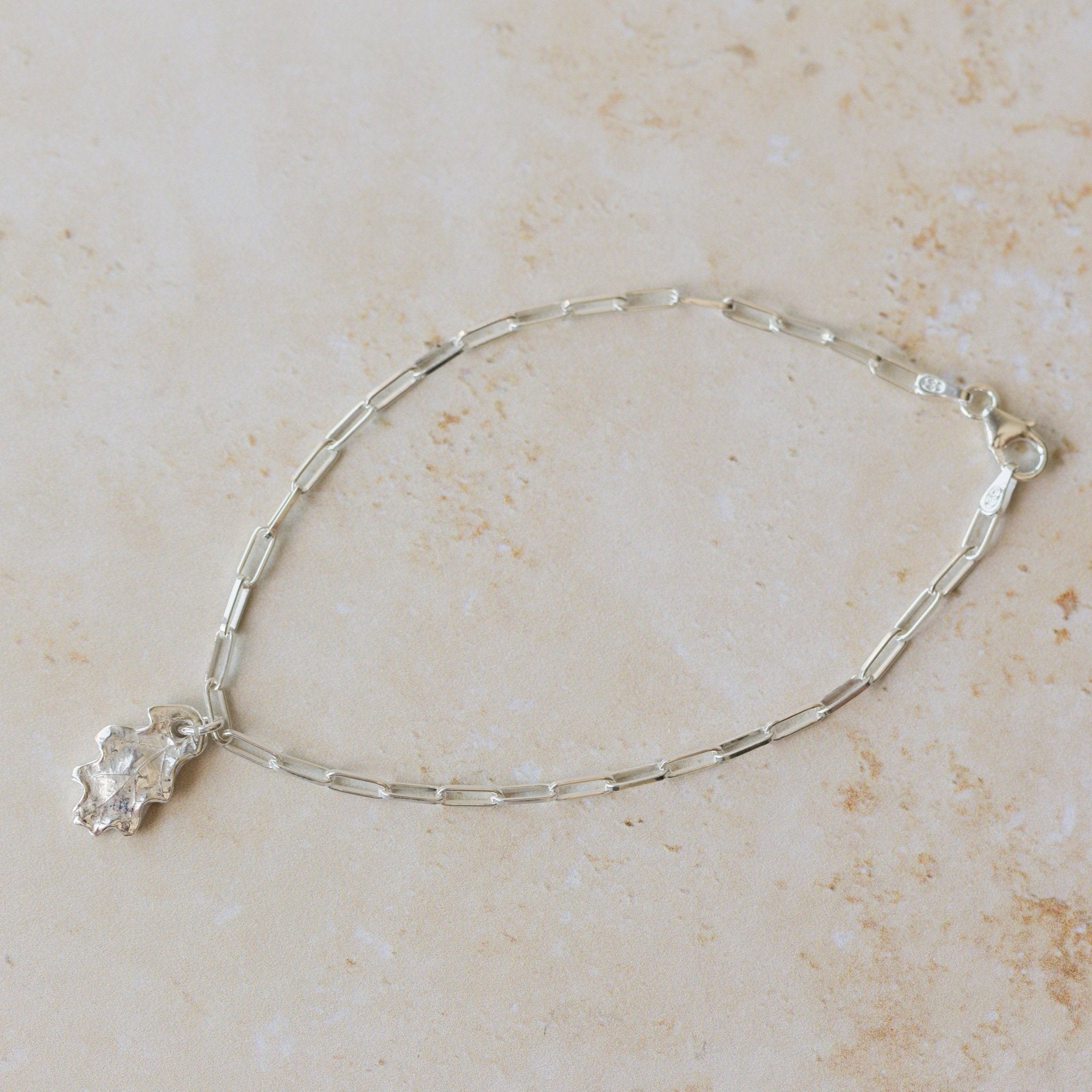 recycled silver oak leaf charm bracelet with paperclip chain styled on soft neutral surface, nature-inspired handmade jewellery by Iris & Lolli