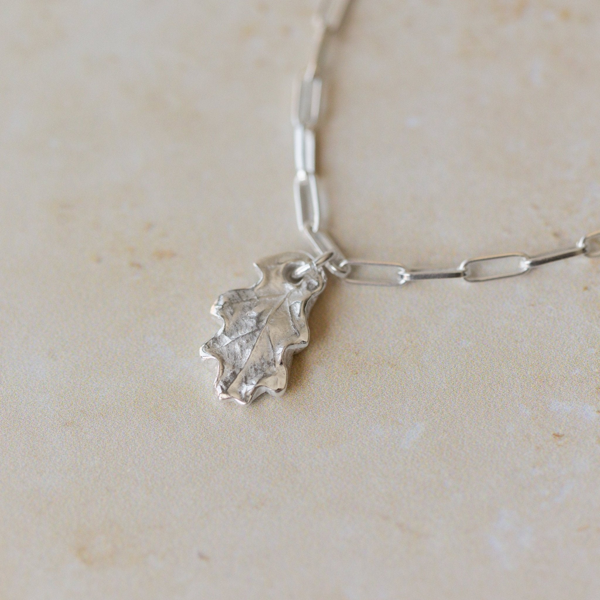silver oak leaf charm bracelet with paperclip chain on neutral stone background, handcrafted recycled silver jewellery by Iris & Lolli