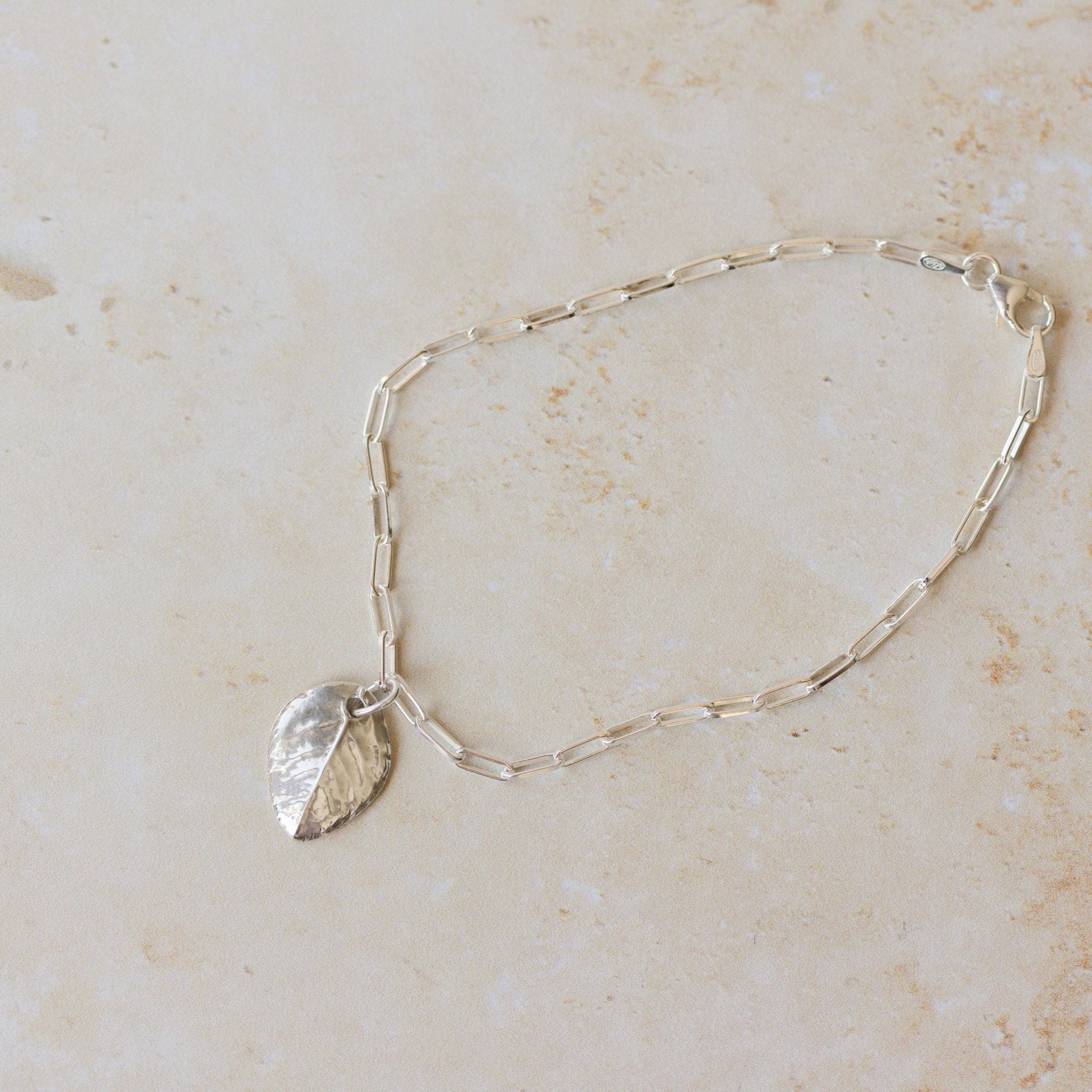 recycled silver rose leaf charm bracelet with paperclip chain on neutral background, handmade botanical jewellery by Iris & Lolli