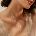 woman wearing fine silver shell pendant necklace on delicate satellite chain, coastal inspired jewellery styled with neutral blouse