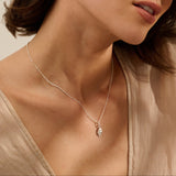 woman wearing fine silver shell pendant necklace on delicate satellite chain, coastal inspired jewellery styled with neutral blouse