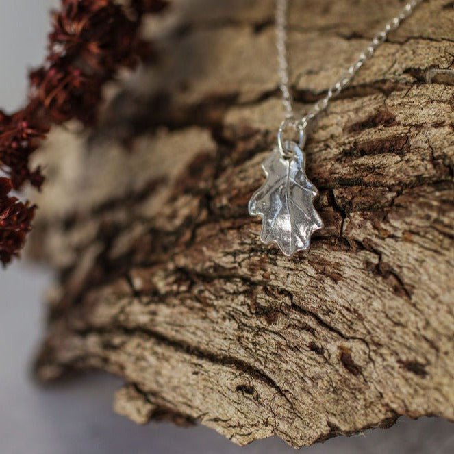 Silver oak leaf necklace on tree bark, botanical silver jewellery handmade in recycled silver UK